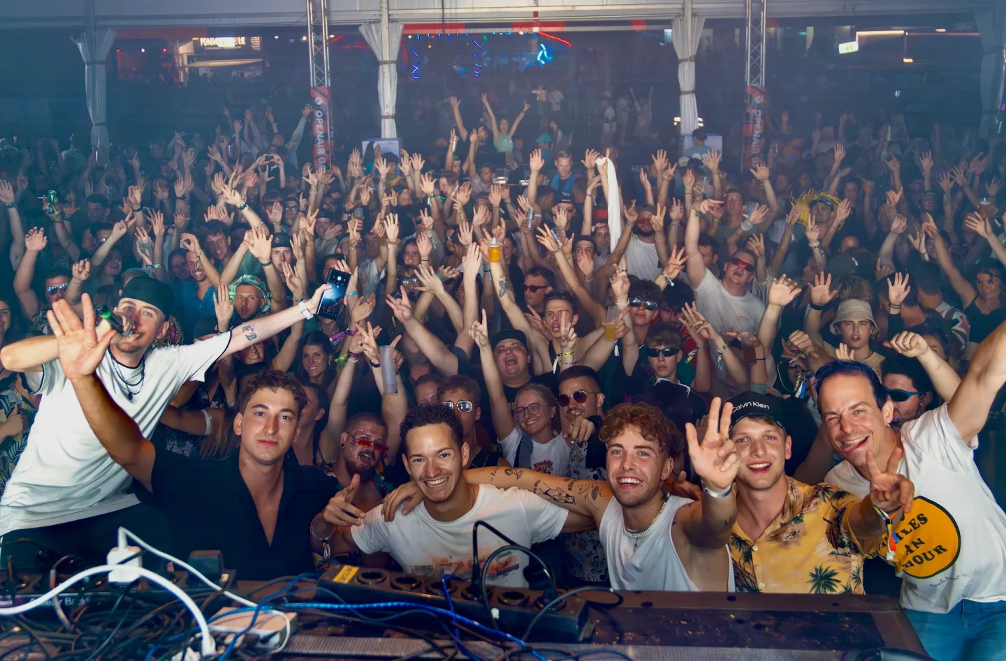 Cale mit lächelnden Gästen vor dem DJ-Pult im Festzelt