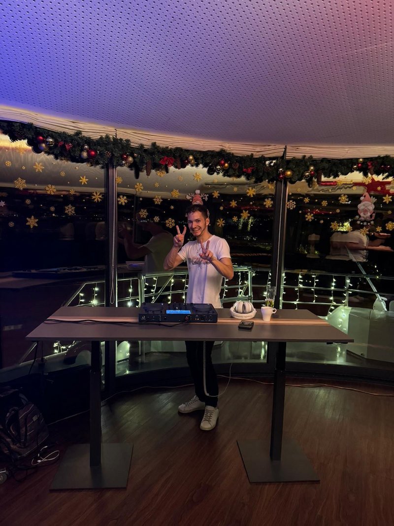 Cale hinter einem kompakten DJ-Setup in einem weihnachtlich dekorierten Raum