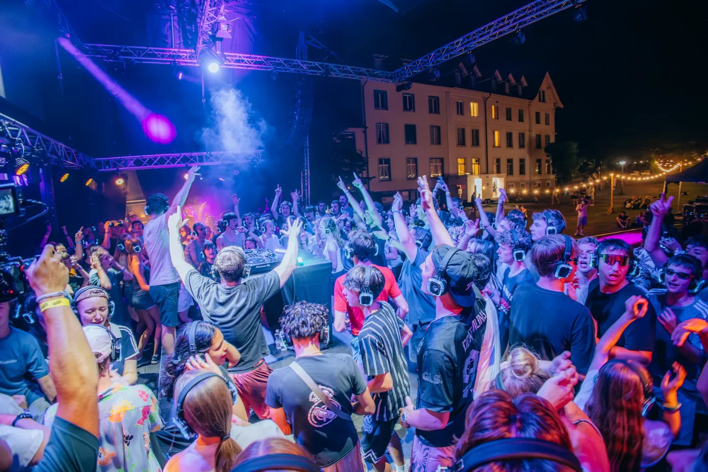 Cale am DJ-Pult bei einer Open-Air-Party mit Kopfhörern im Publikum
