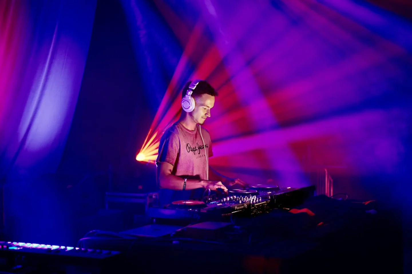 Cale am DJ-Pult unter magenta- und blauem Bühnenlicht